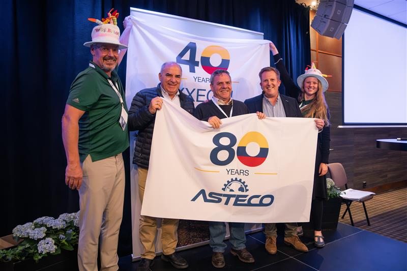 People holding a flag that says "80 years Asteco"