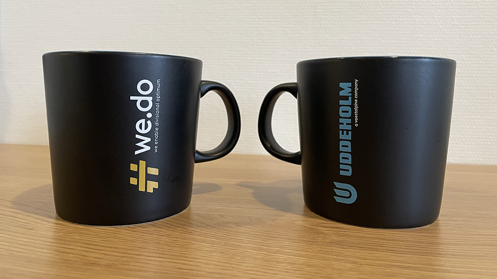 Coffee mugs with the Uddeholm logo and the  #we.do logo