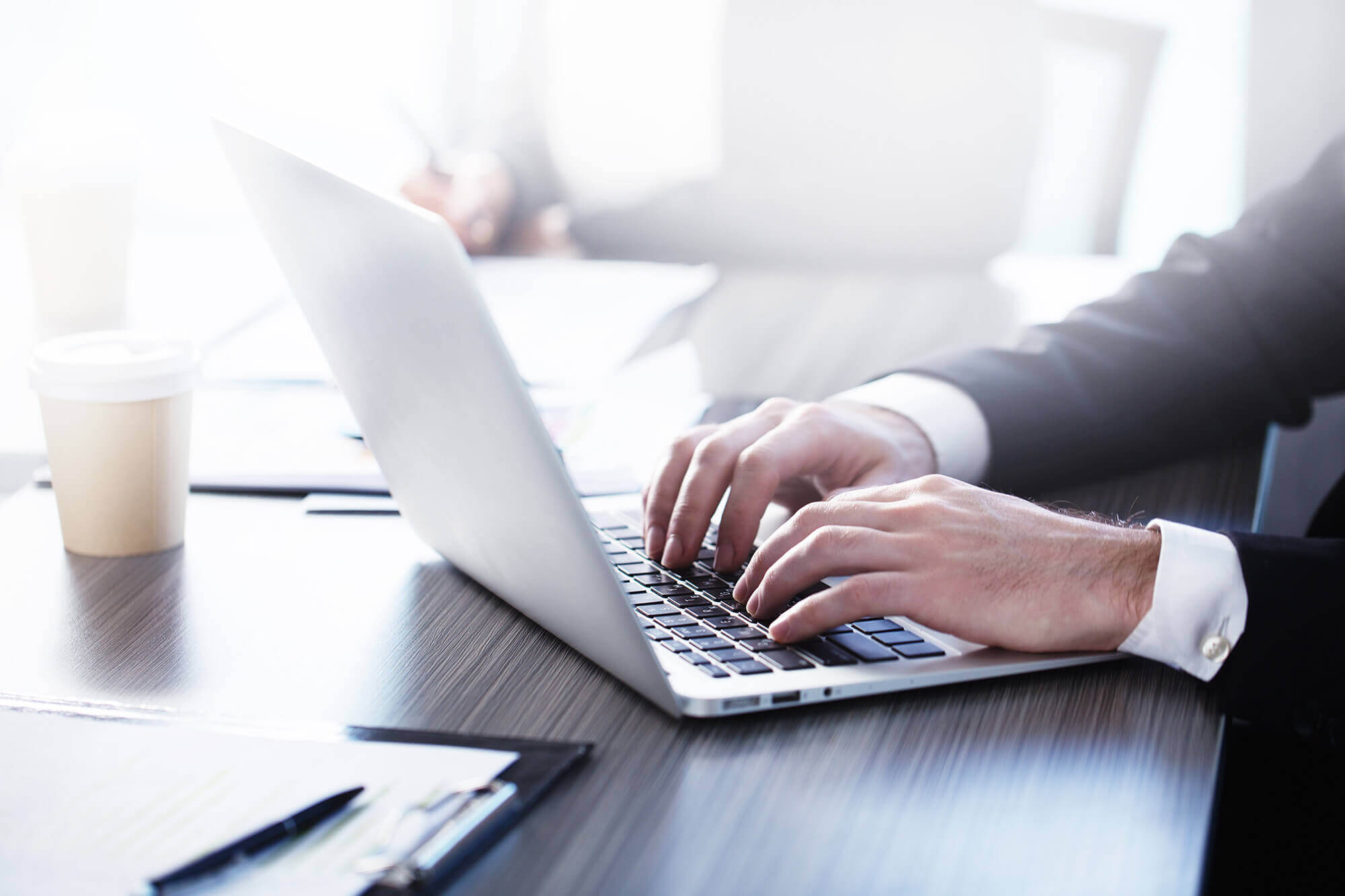 close-up of a man's hands typing on a laptop keyboard